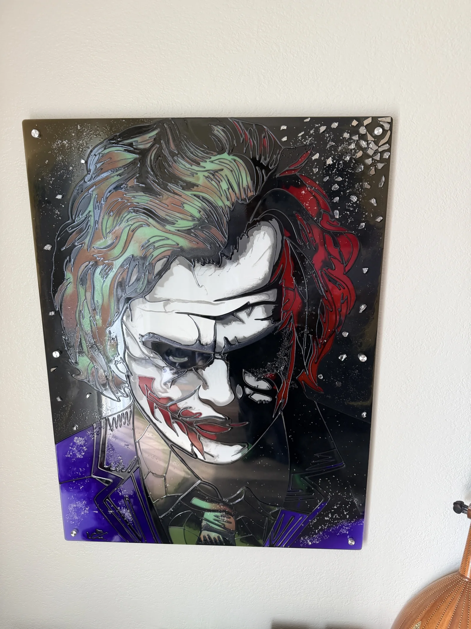 The Joker mounted on silver standoffs against a pale wall in even daylight.